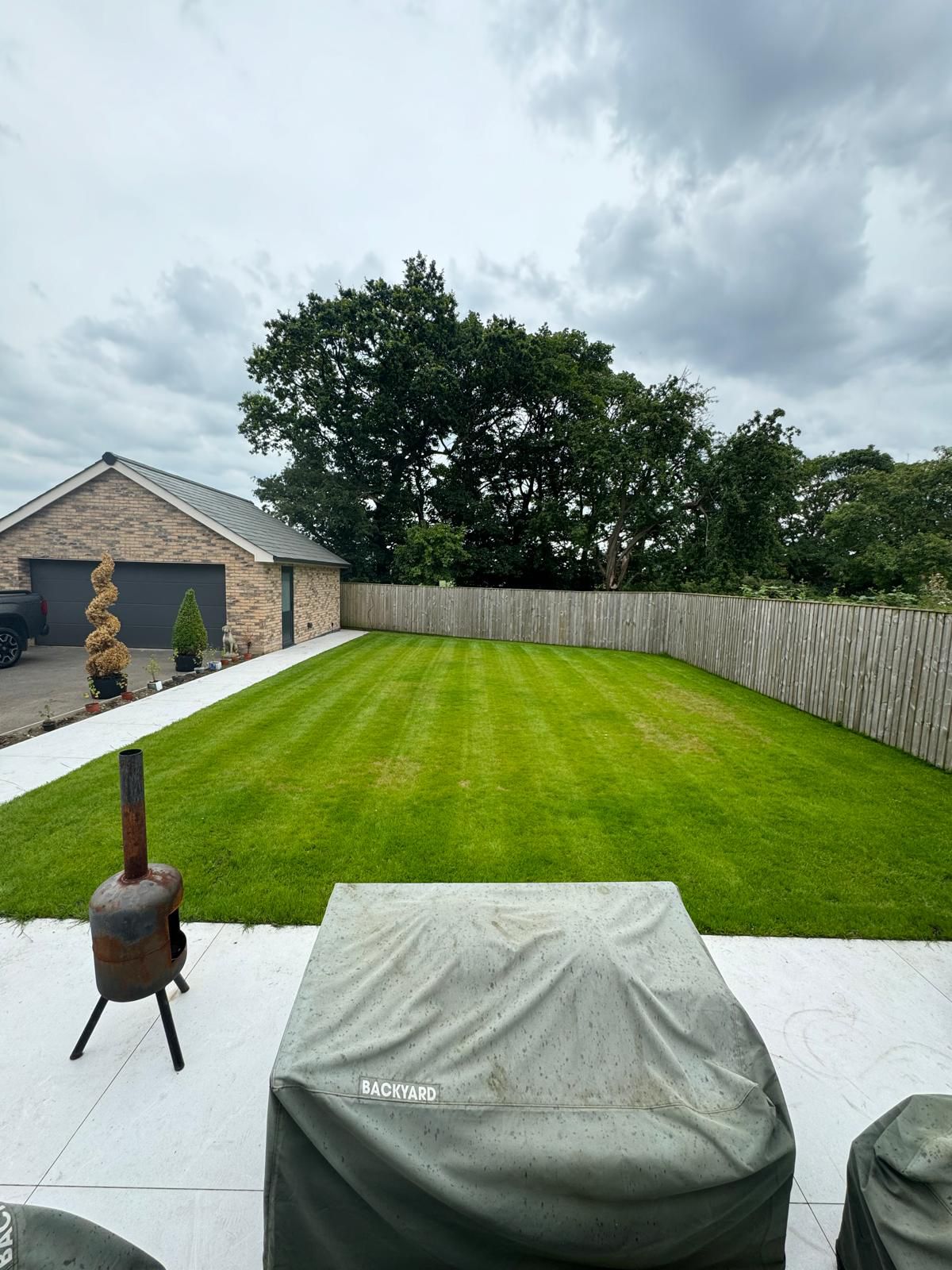Landscaped rear garden with striped lawn, fencing and patio