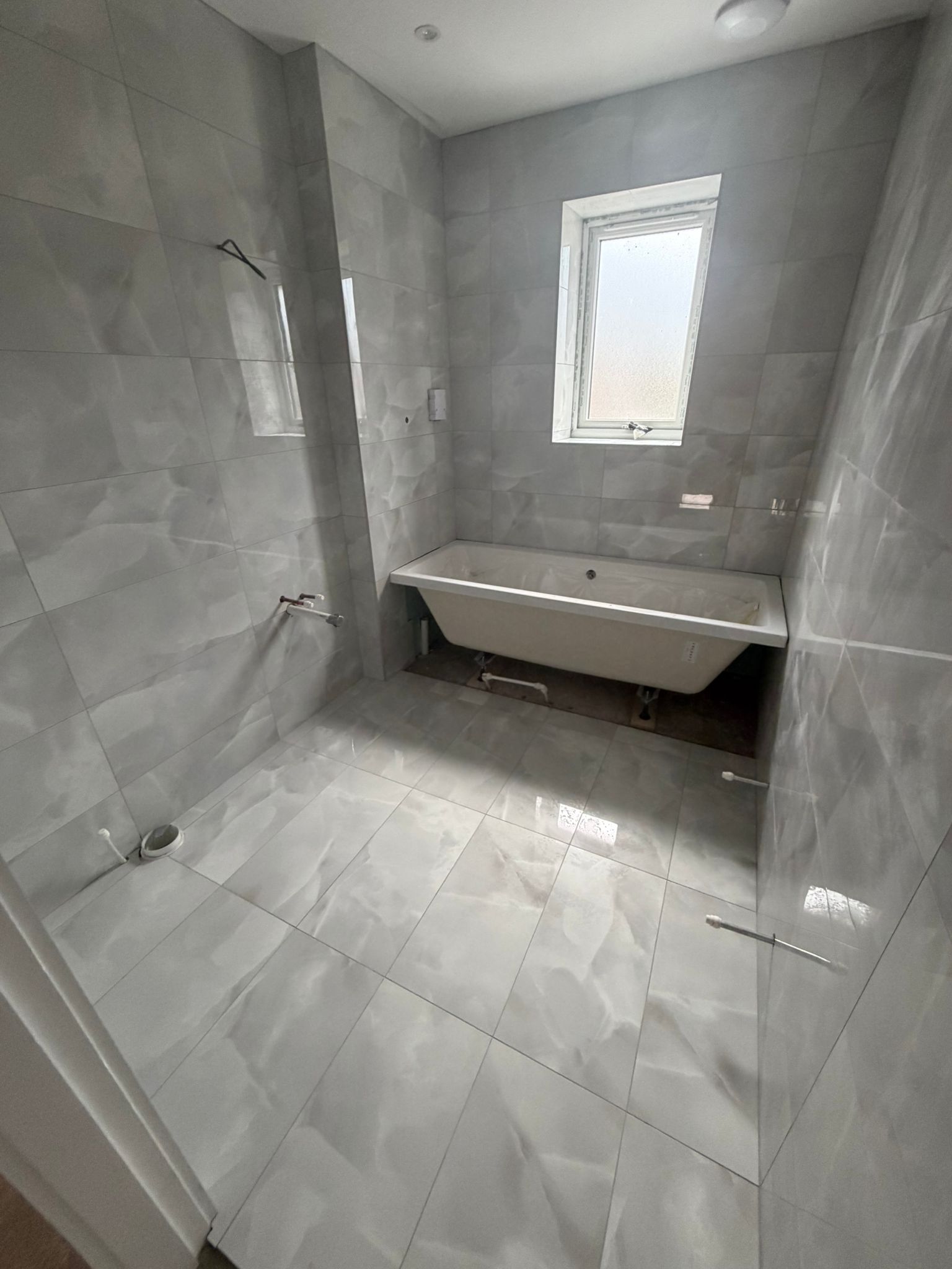 Family bathroom with grey marble tiling and freestanding bath